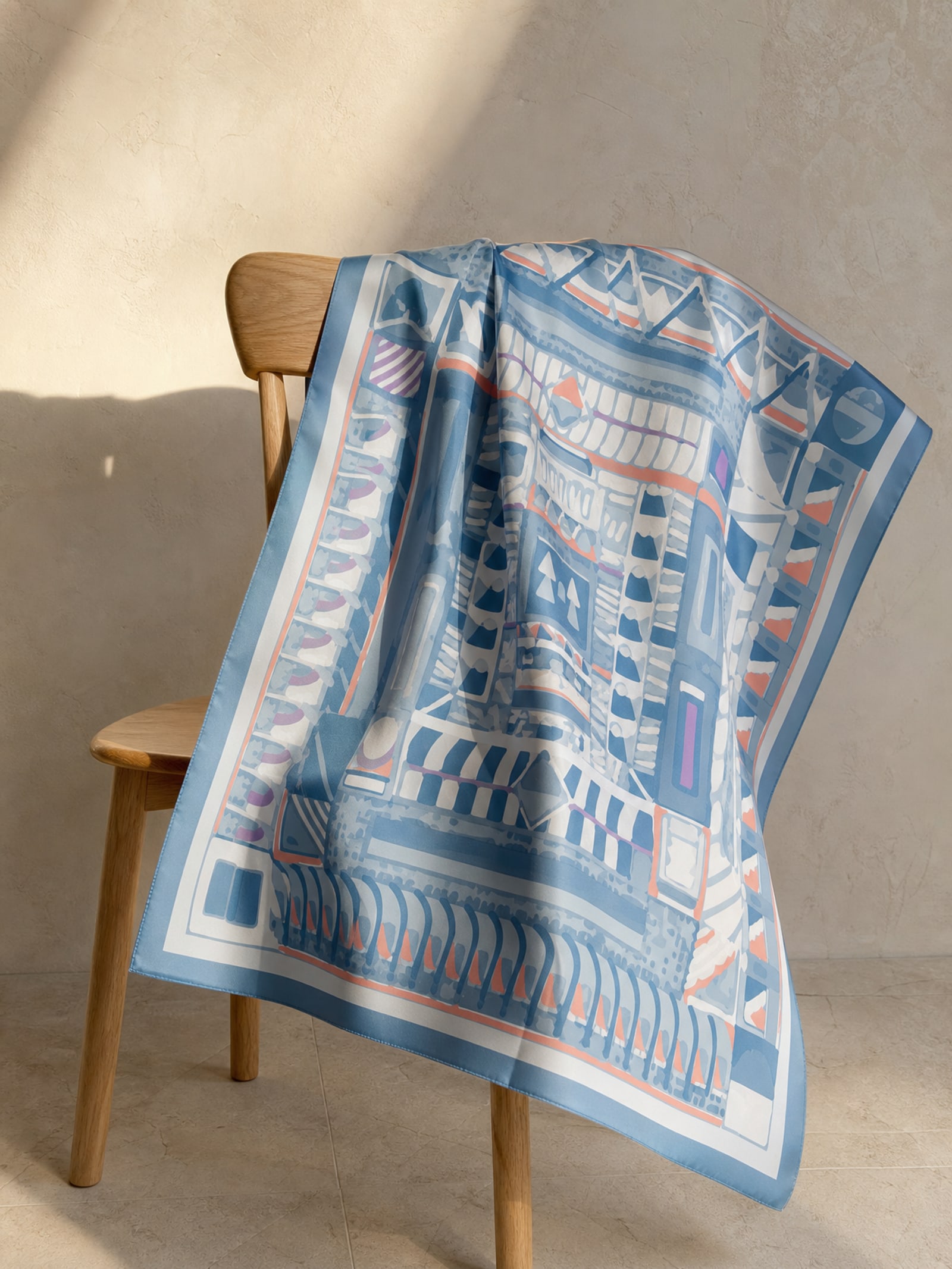 A printed silk scarf thrown over the back of a pale oak chair